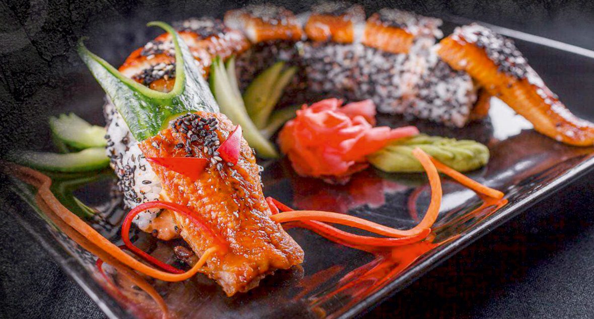 Dragon Roll mit gegrilltem Aal auf schwarzem Teller